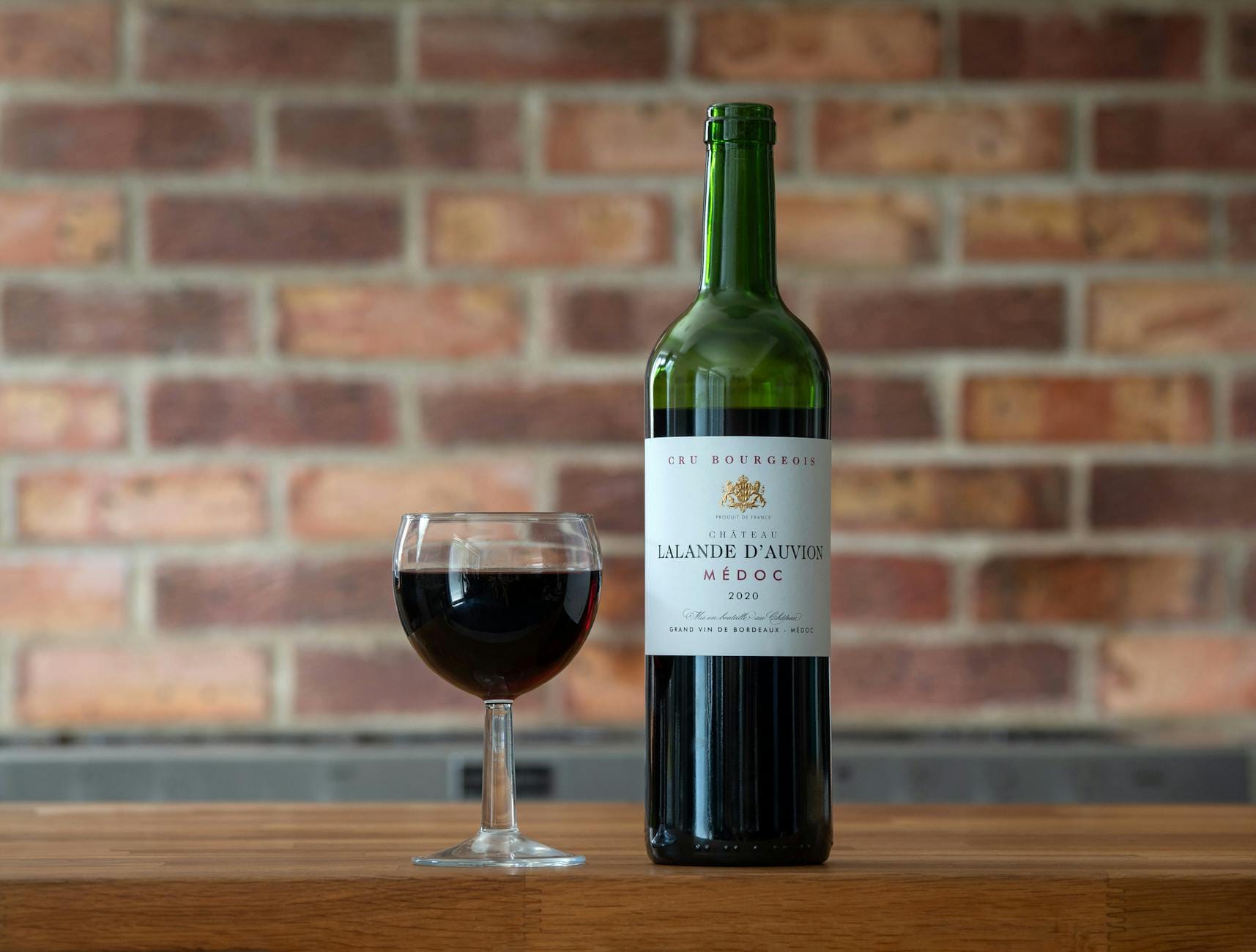 Butelka czerwonego Bordeaux Chateau Lalande D'Auvion 2020 i kieliszek na stole