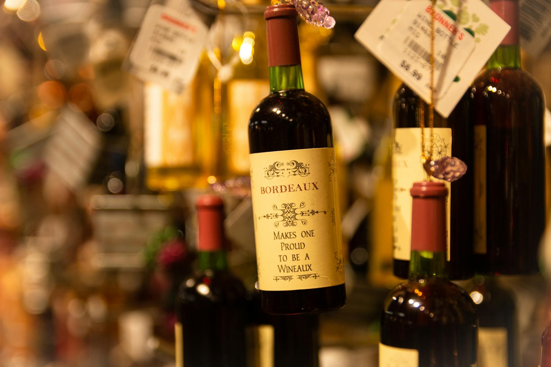 Butelki Bordeaux różnych chateau z cenami na półce sklepu z winem