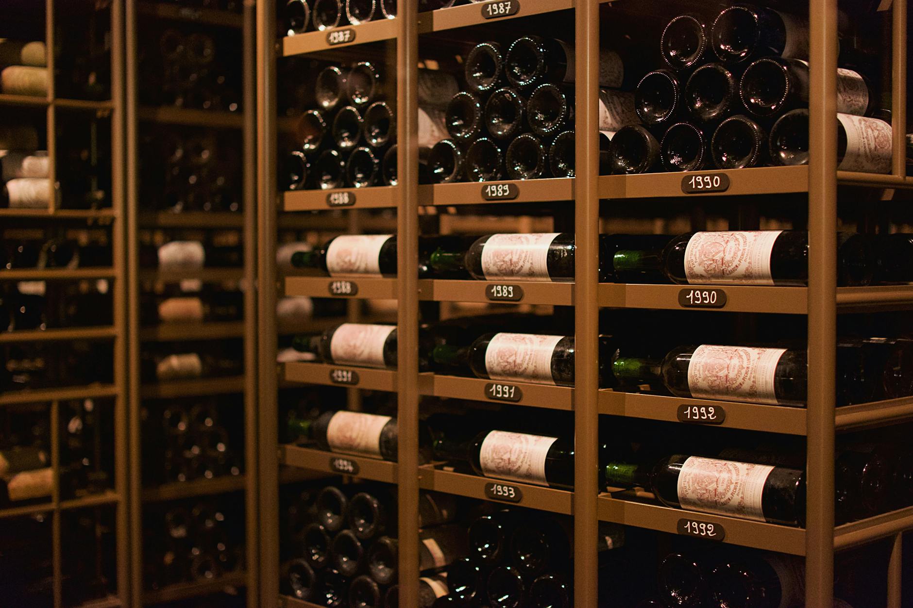 Stare butelki wina ułożone na półkach w piwnicy w Pauillac