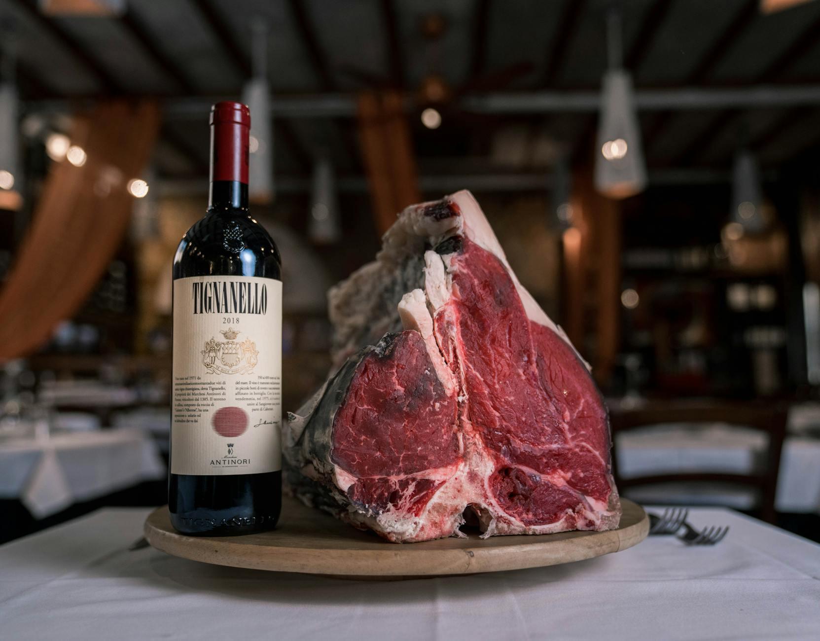 Surowy stek z butelką czerwonego Bordeaux na restauracyjnym stole Surowy stek z butelką czerwonego Bordeaux na restauracyjnym stole