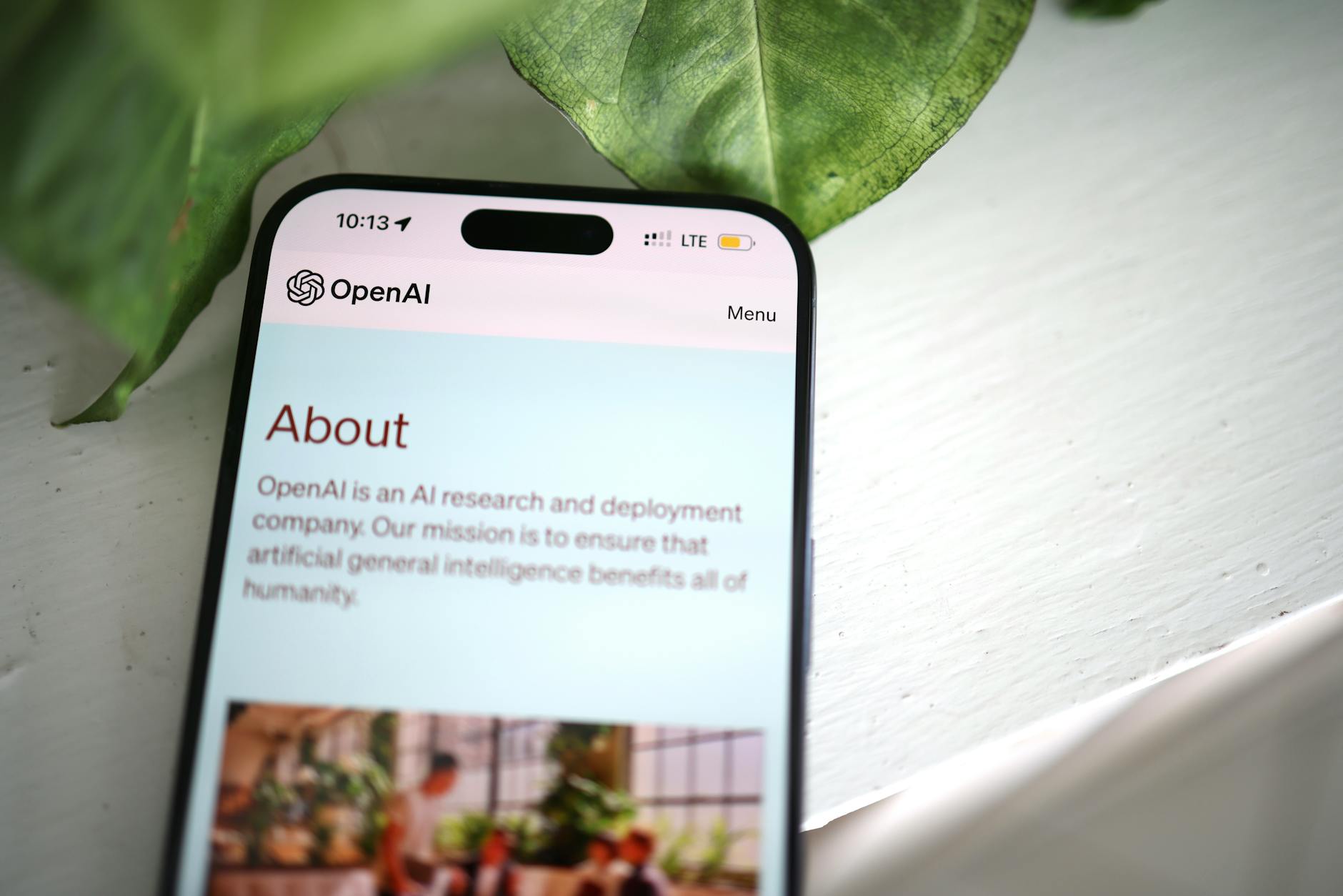 Zbliżenie ekranu smartfona z witryną OpenAI na tle zieleni