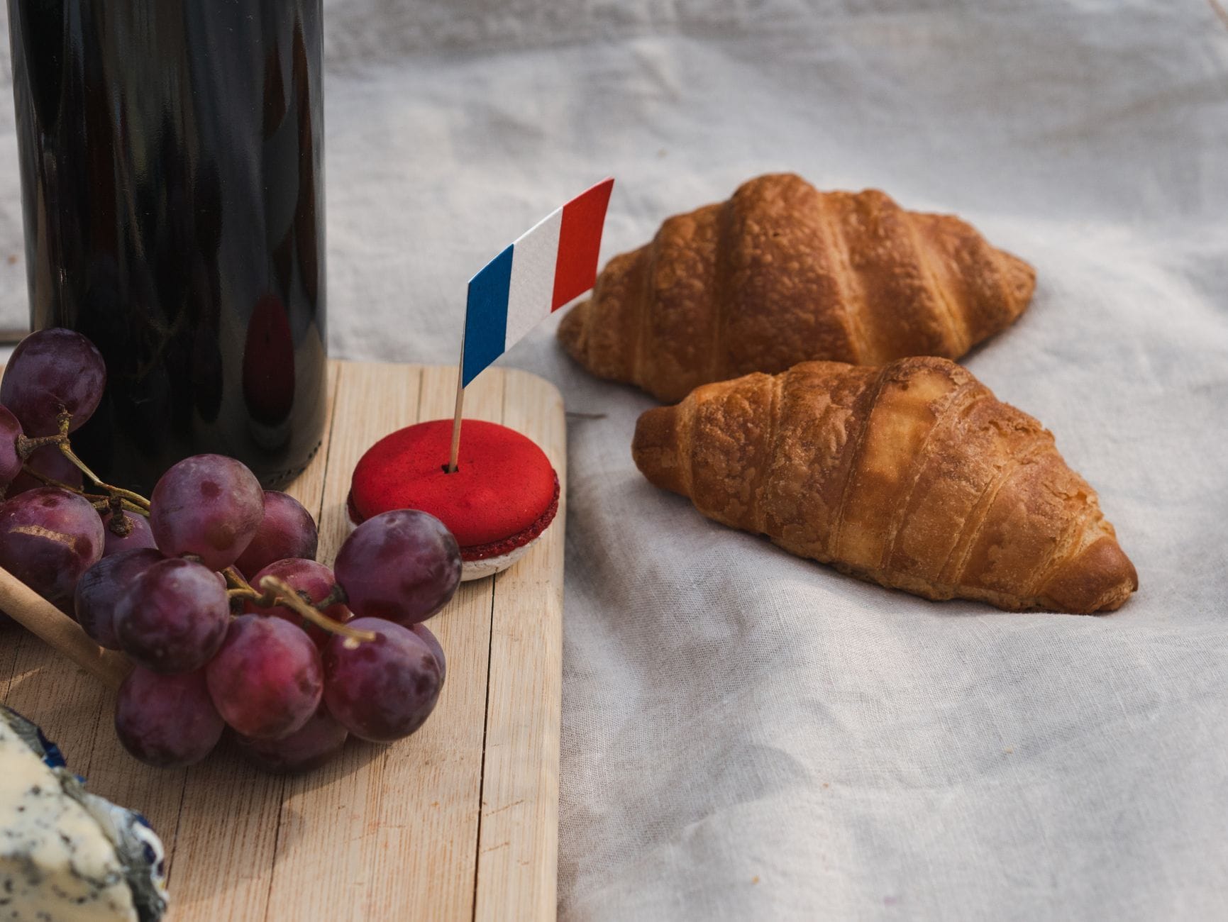 Croissanty, czerwone makaroniki i winogrona z małą flagą Francji