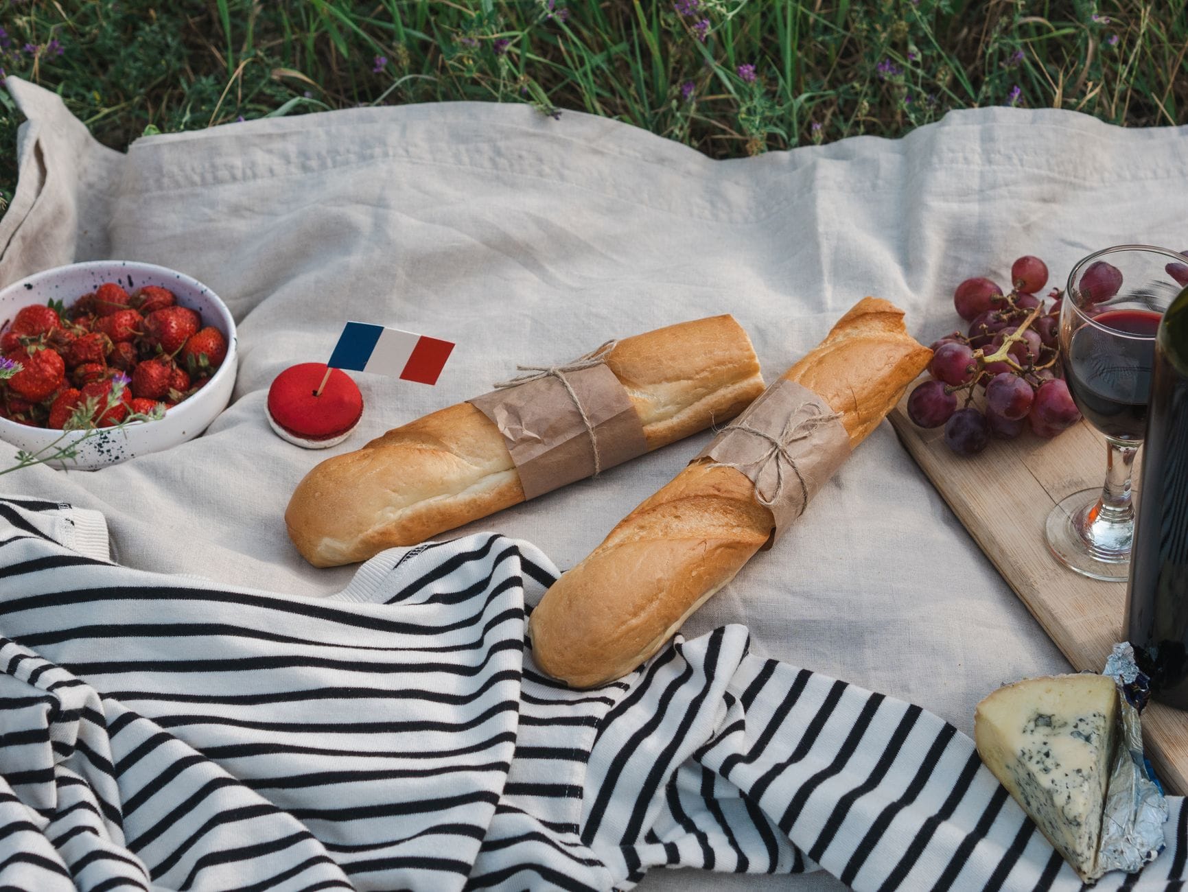 Piknik na świeżym powietrzu z bagietką, serem, winem i flagą Francji