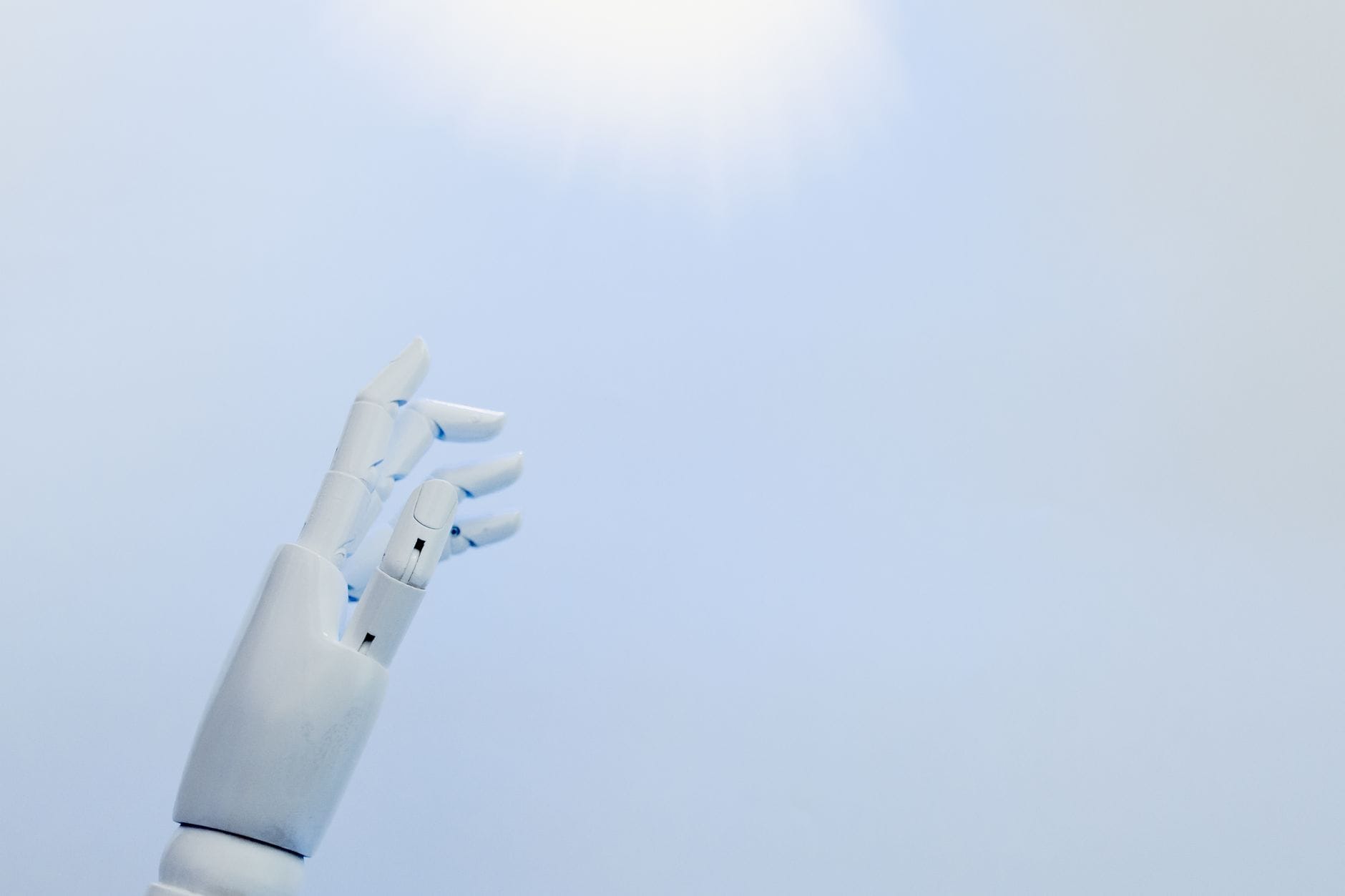 Robotyczna dłoń wyciągnięta w stronę jasnego światła na białym tle