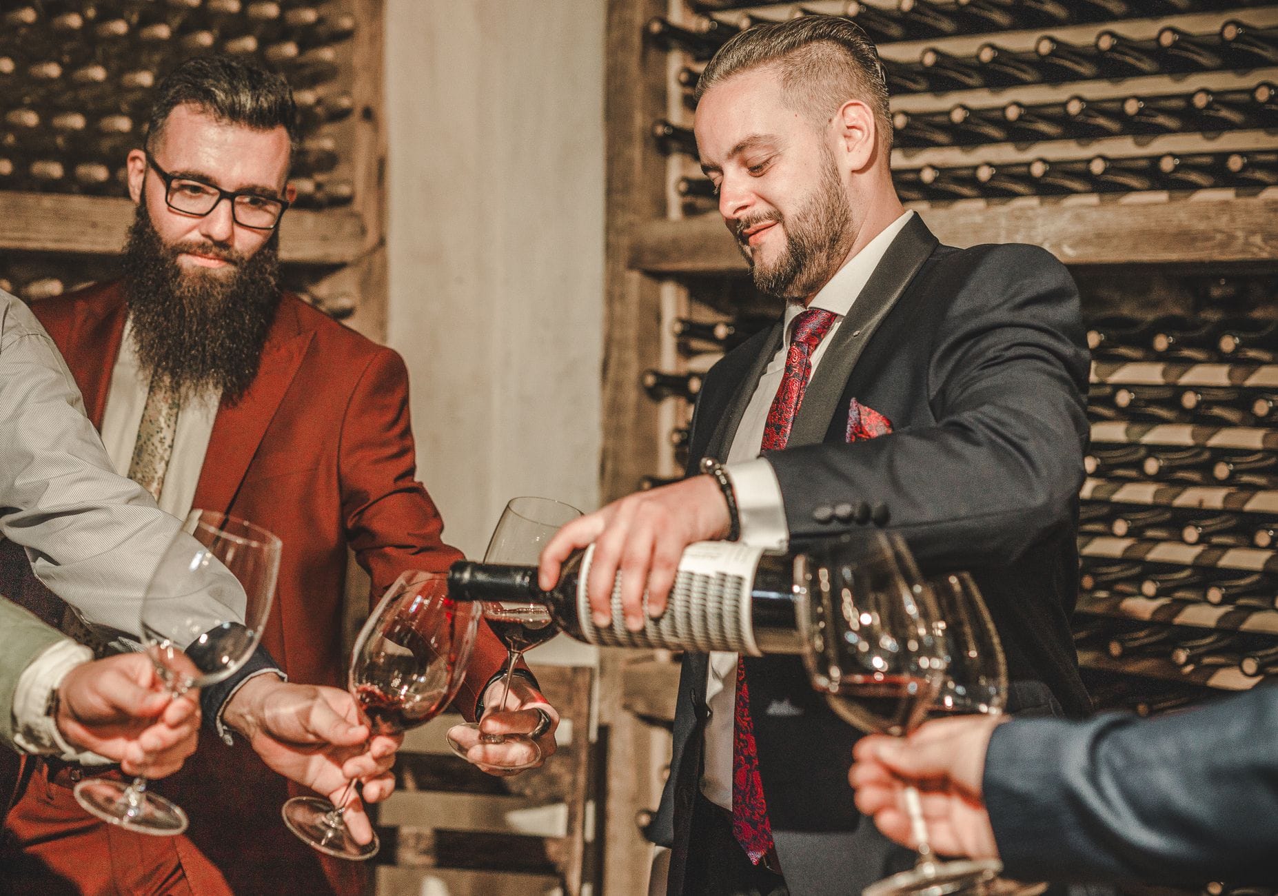 Dwaj mężczyźni w garniturach degustują wino w eleganckiej piwnicy